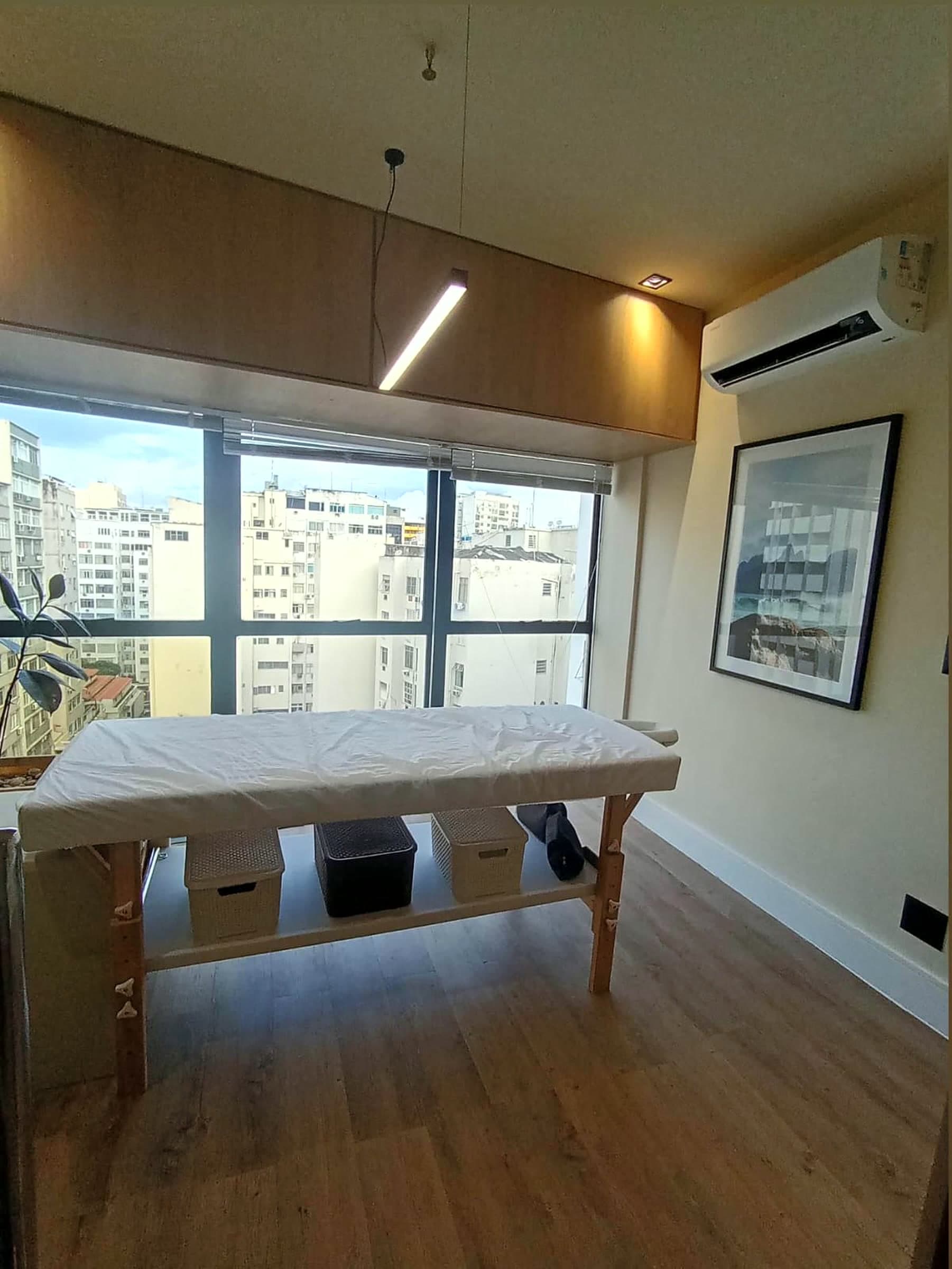 Sala de atendimento com maca e janela ampla com vista da cidade