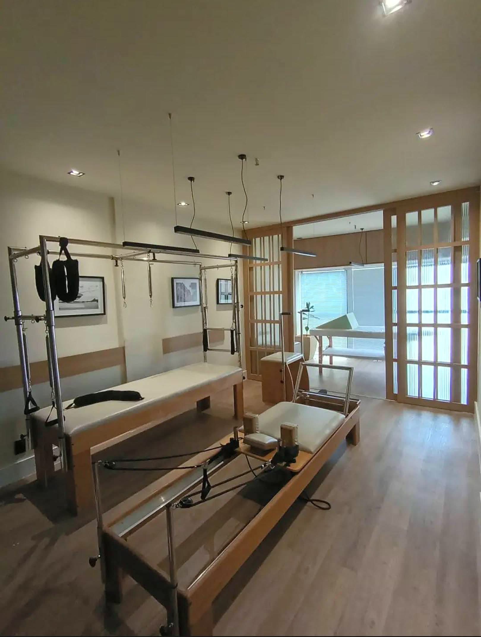 Estúdio de Pilates da Clínica Labrum com reformer, cadillac e divisórias de madeira banhadas de luz natural
